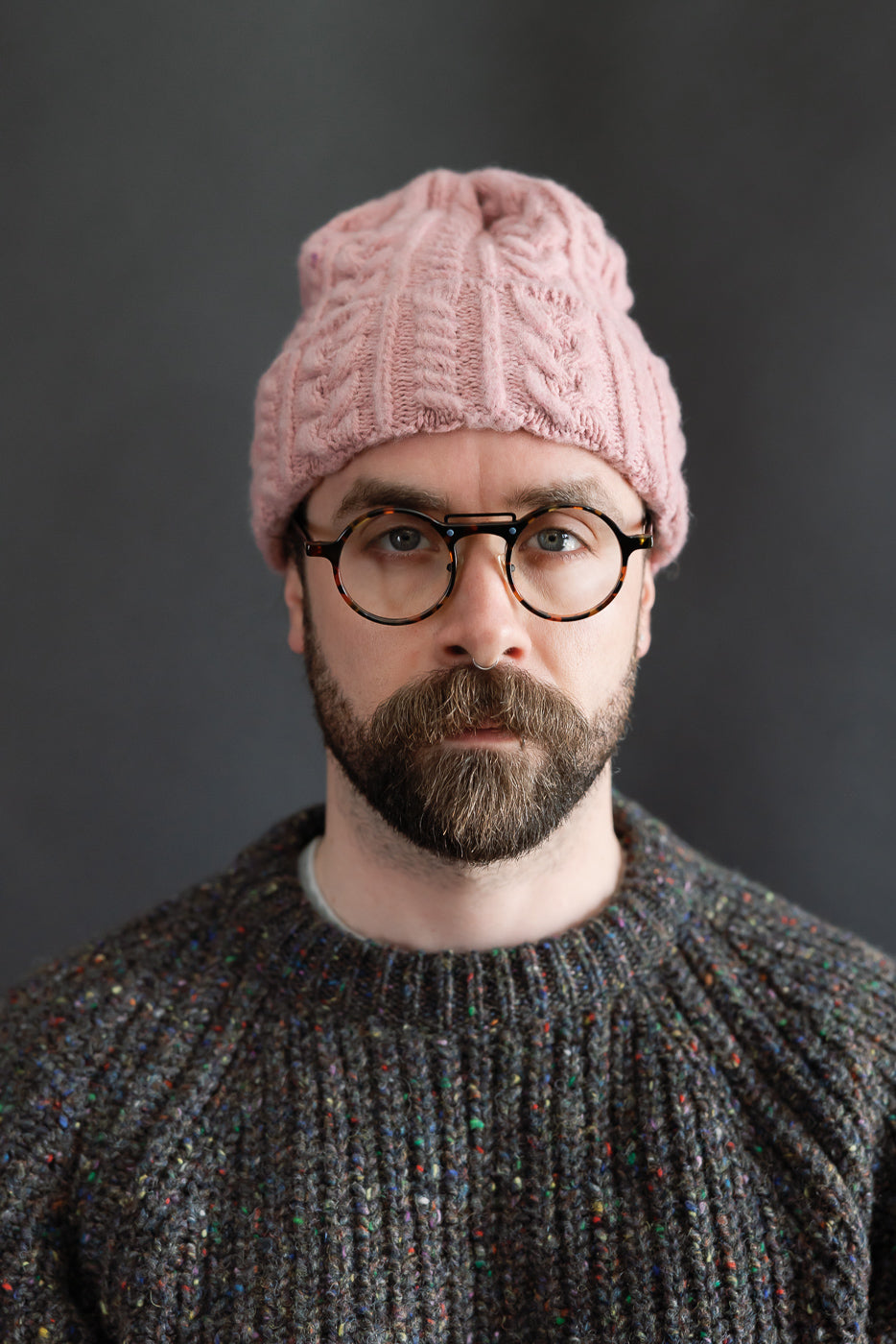 Close-up front view of soft pink cable knit beanie on male model, 5'9