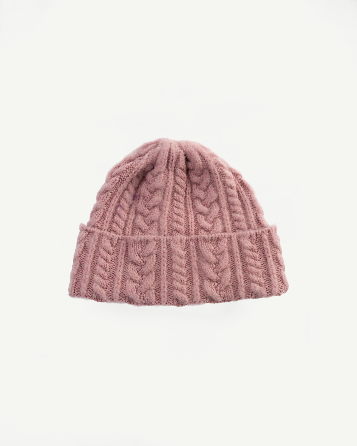 Front view flat lay of soft pink cable knit festival hat, showing textured pattern and ribbed cuff
