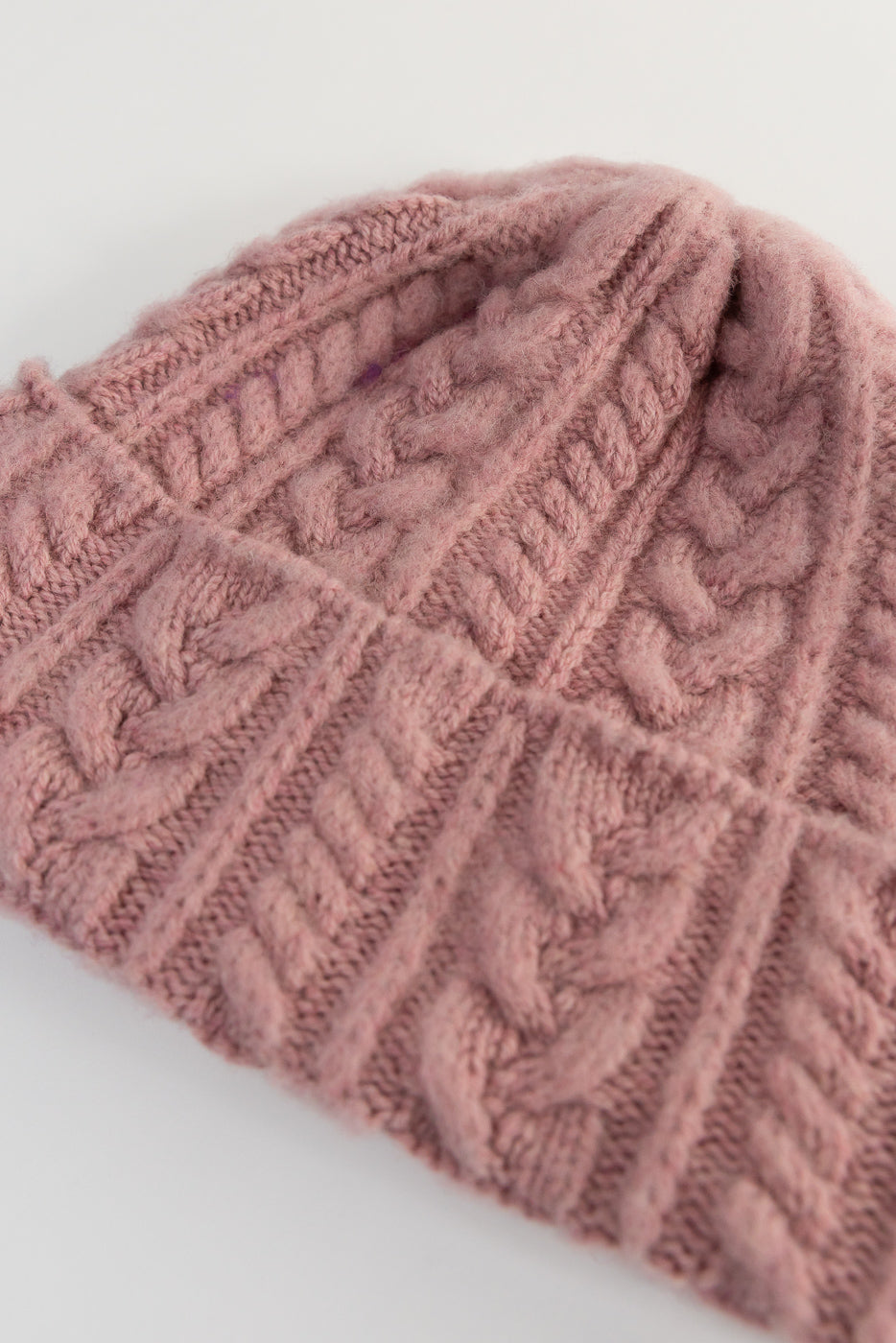 Close-up of soft pink cable knit beanie hat front, showing textured knit detail, Dant