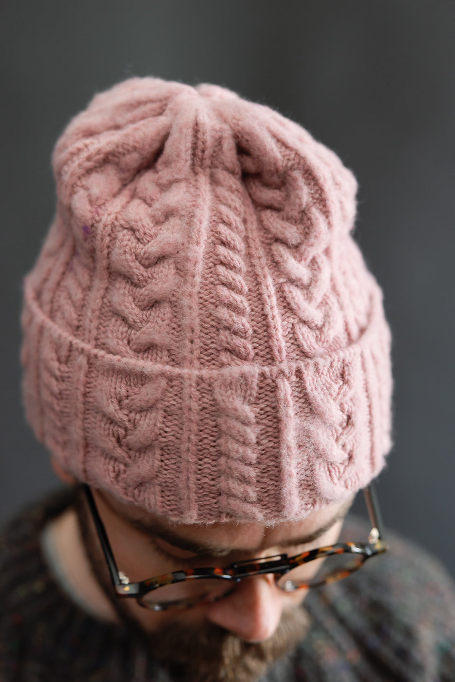 Close-up front view of soft pink cable knit festival hat on male model, 5'9