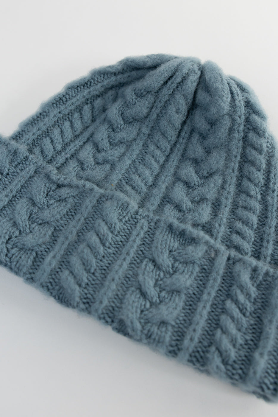 Close-up of soft blue cable knit festival hat showing front texture and ribbed cuff, Dant