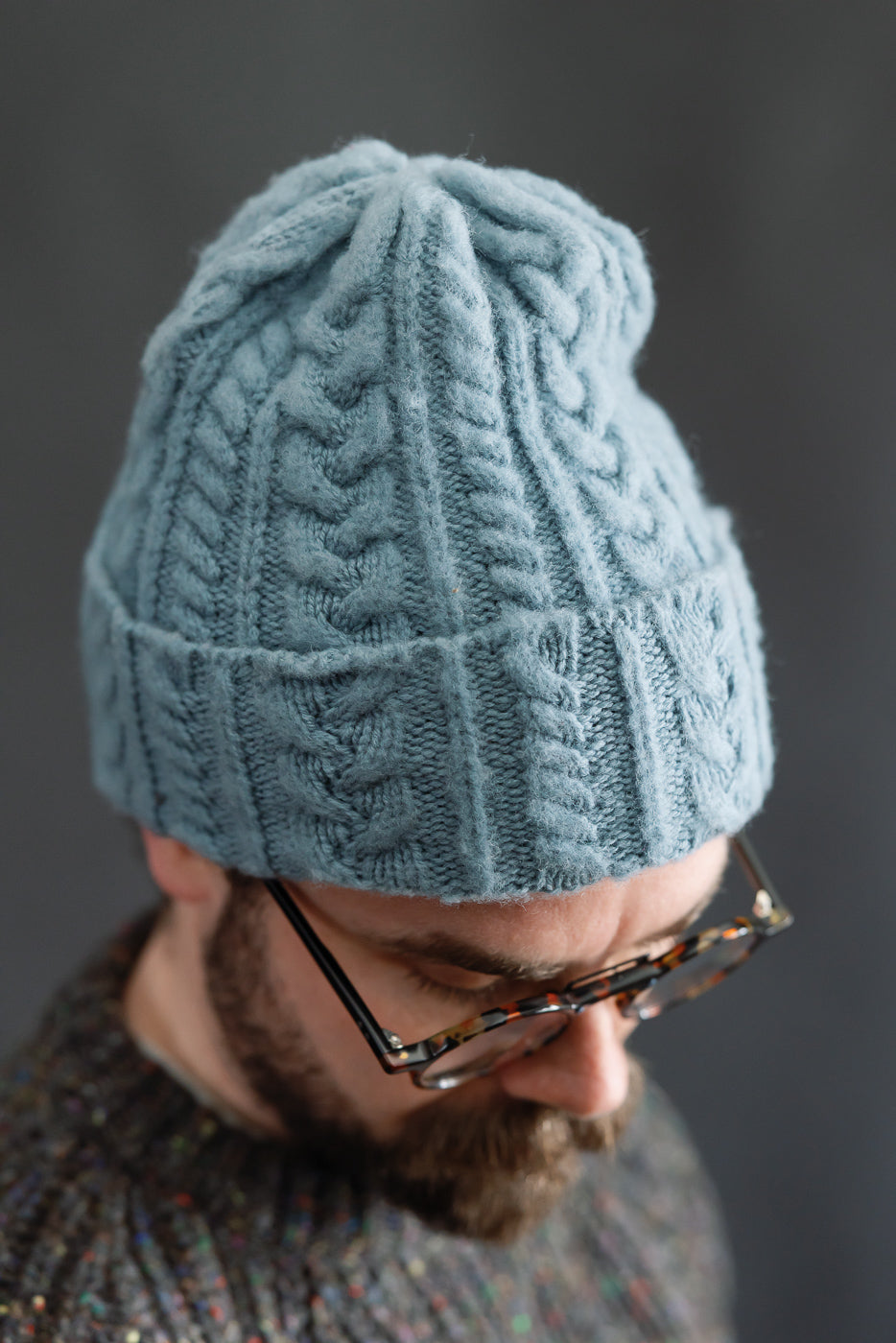 Close-up of cable knit soft blue beanie on male model, 5'9
