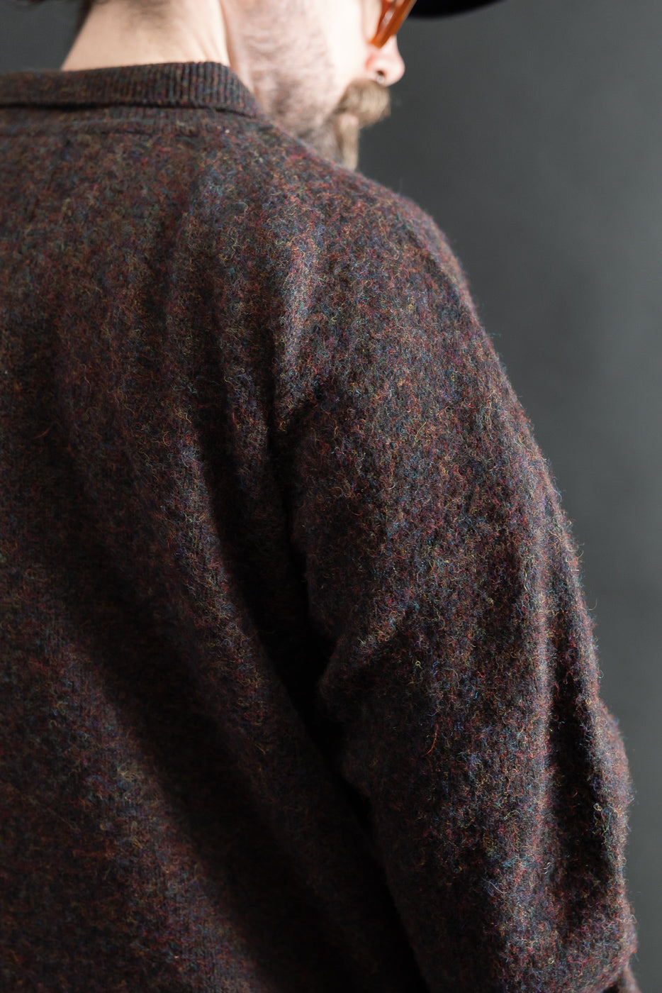 Close-up of back and shoulder texture on multicolor knit sweater; male model, athletic build, partial rear view.
