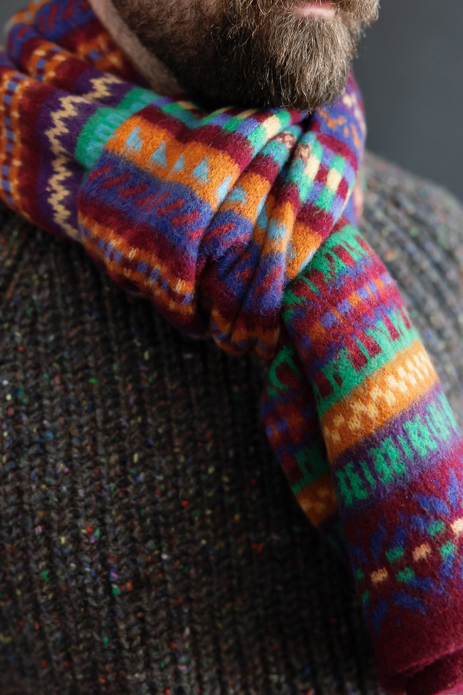 Close-up of colorful knit Howlin Future Is Mixed Up scarf on male model, 5'9