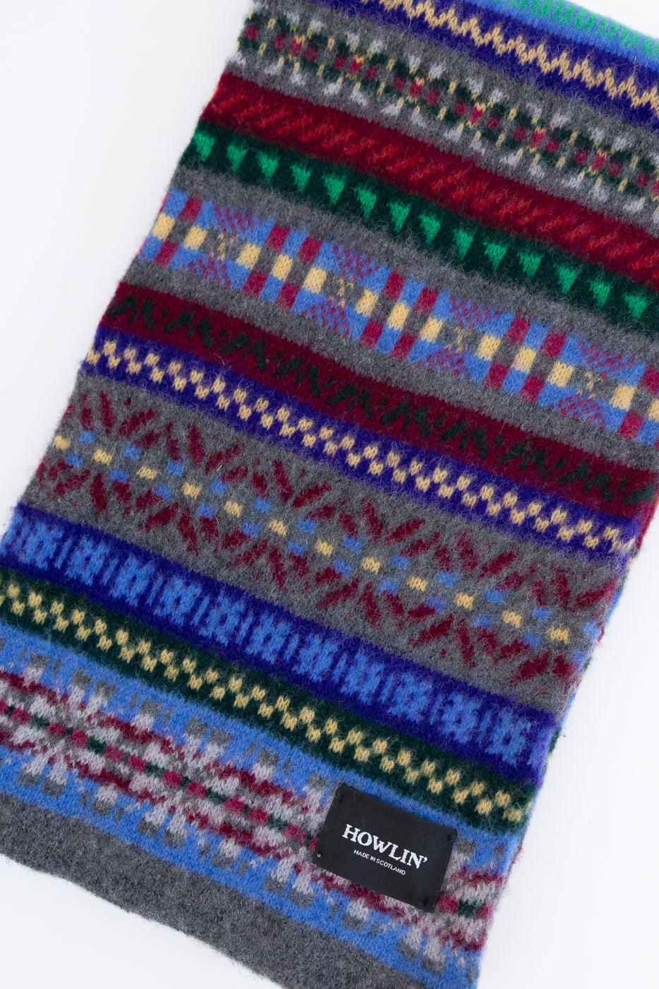 multicolored, patterned wool scarf with a heather grey base on a white background, close up
