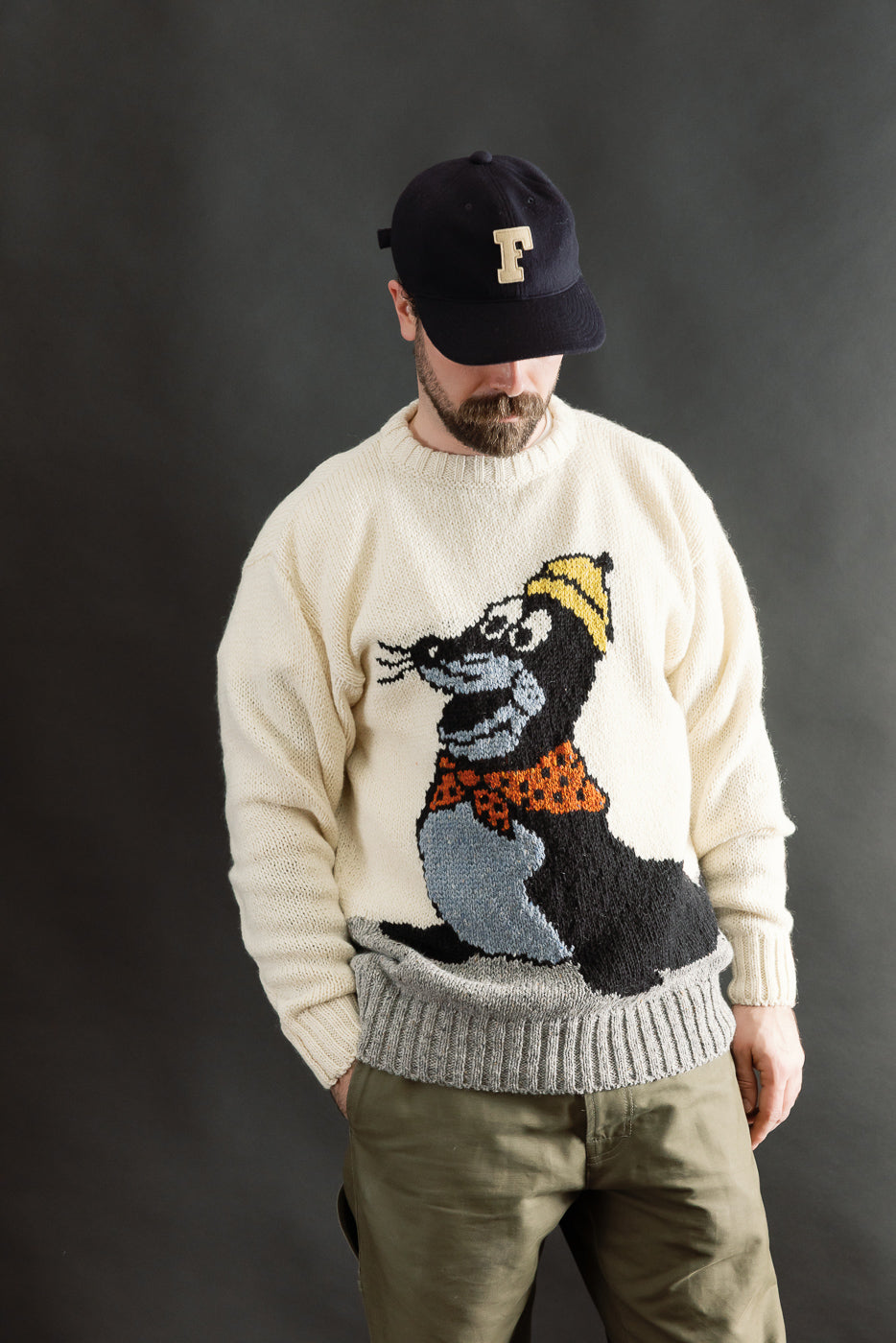 Front view, male model 5'9 165lbs athletic build in cream knit sweater with playful seal graphic, ribbed cuffs and hem, Dant contemporary casual apparel