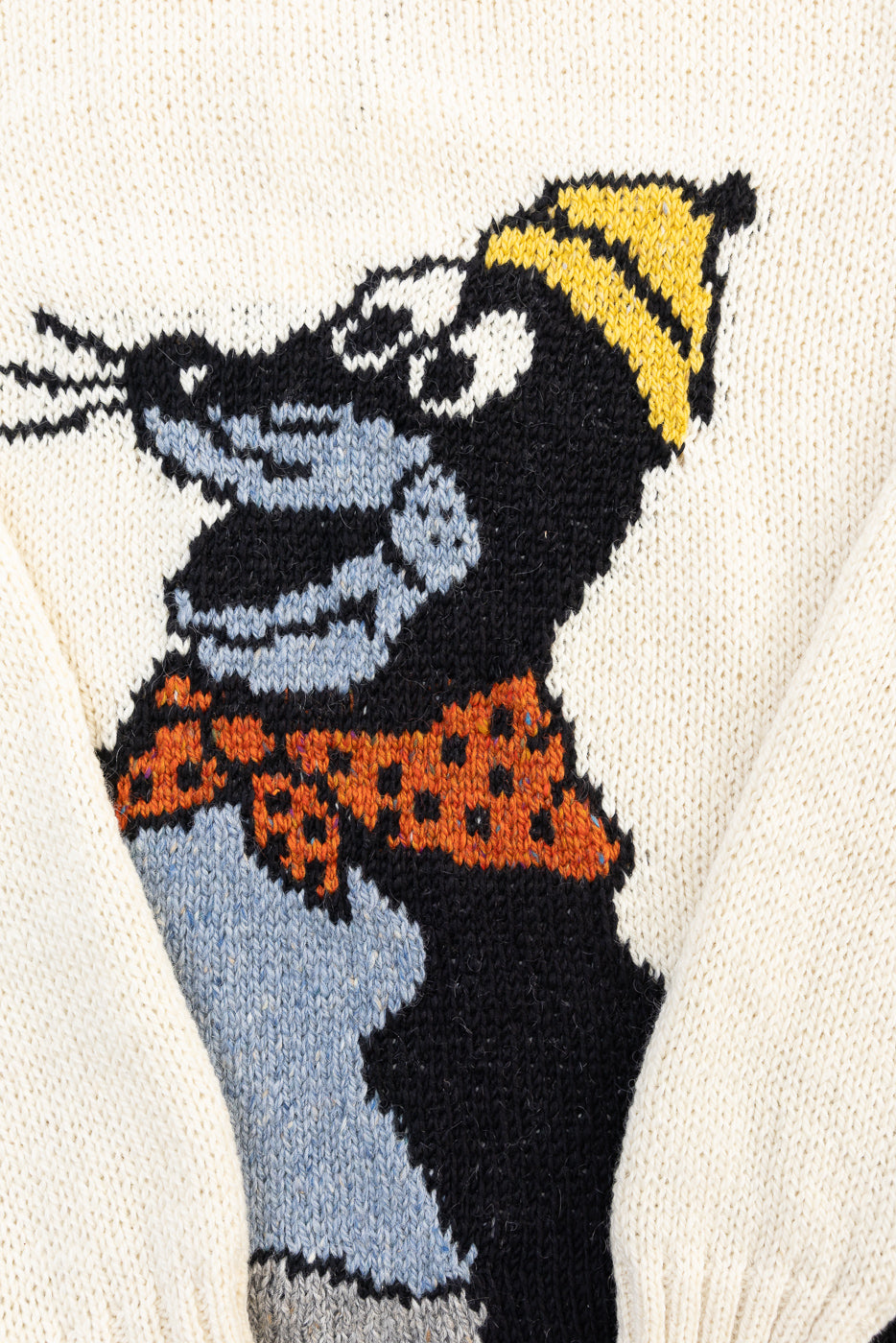 Close-up front detail of knit sweater showing cartoon dog graphic with yellow hat and orange scarf, highlighting fabric texture at Dant contemporary apparel.