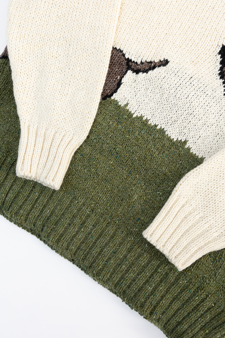 Close-up of front hem and sleeves of Howlin' knit sweater, showing thick ribbed cuffs and green textured knit, Dant contemporary casual apparel.
