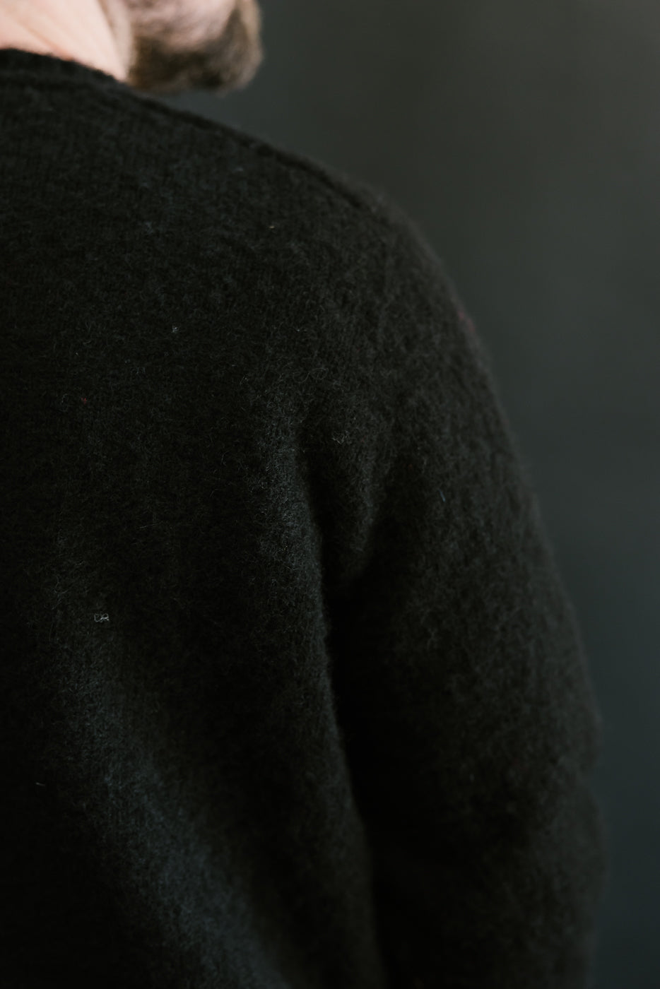Person wearing a black sweater against a dark background