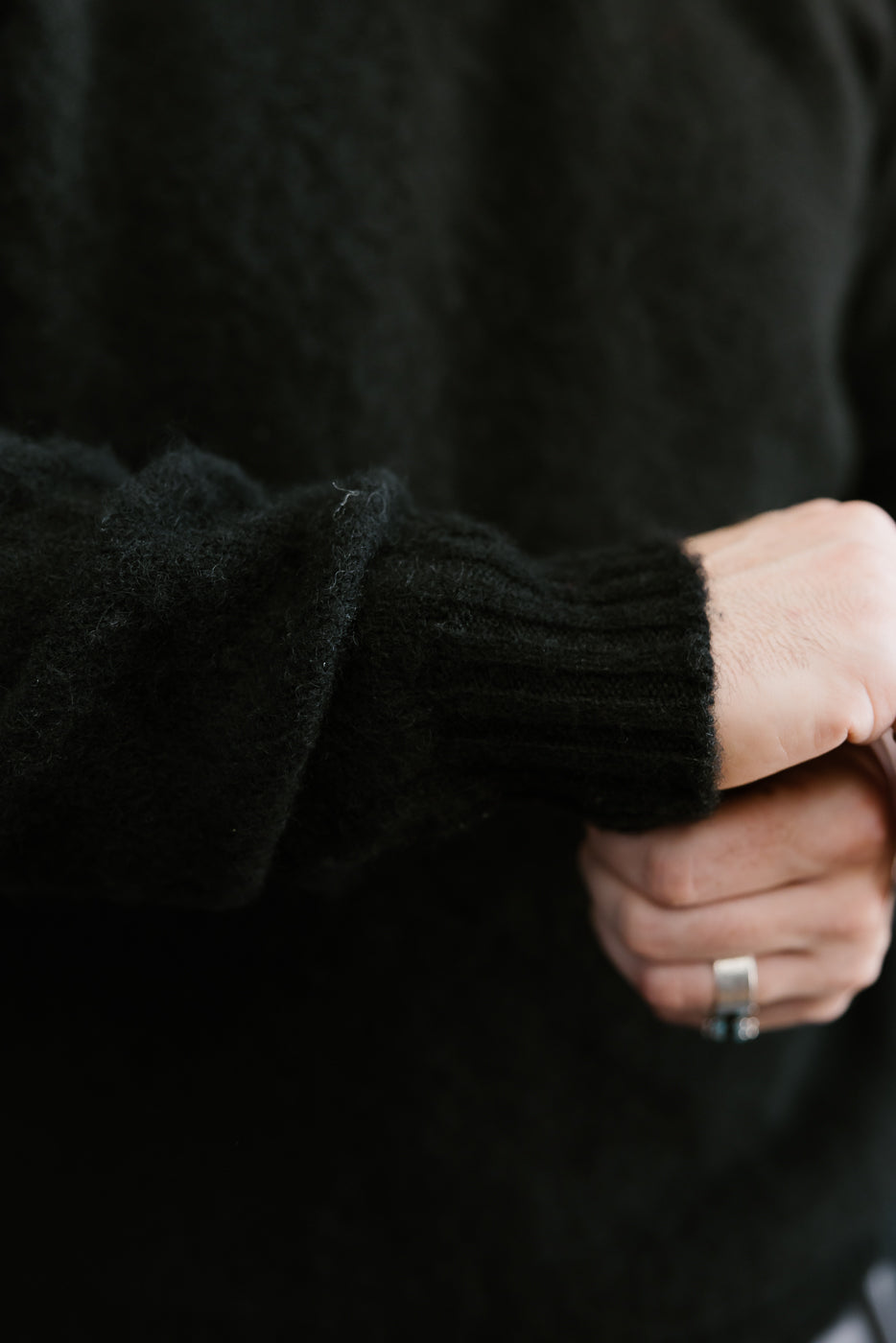 Close-up of a person wearing a black sweater with a blurred background
