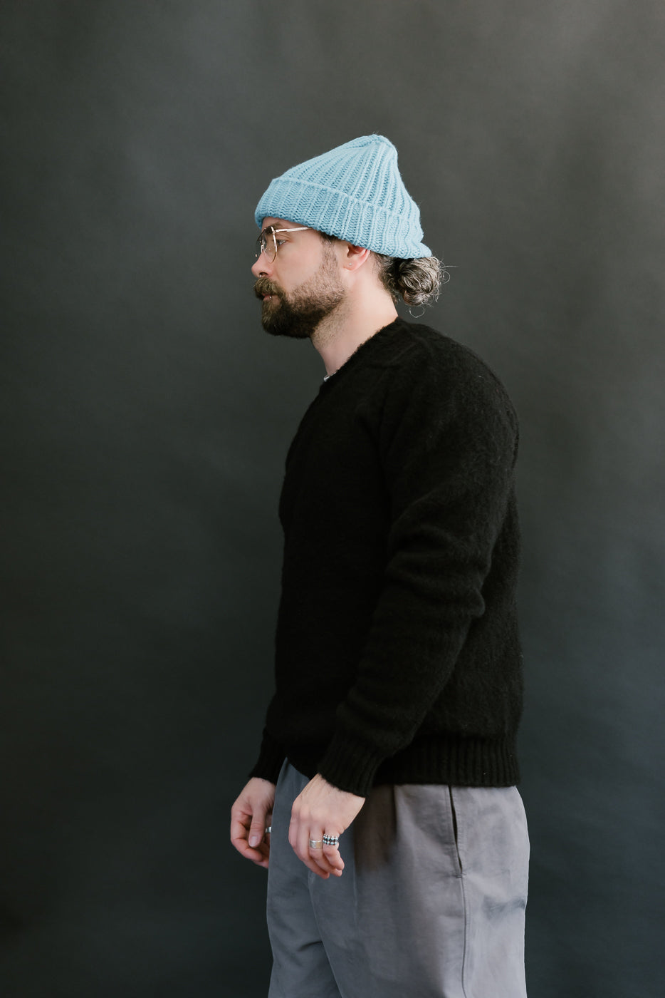 Man wearing a blue beanie and black sweater against a dark background