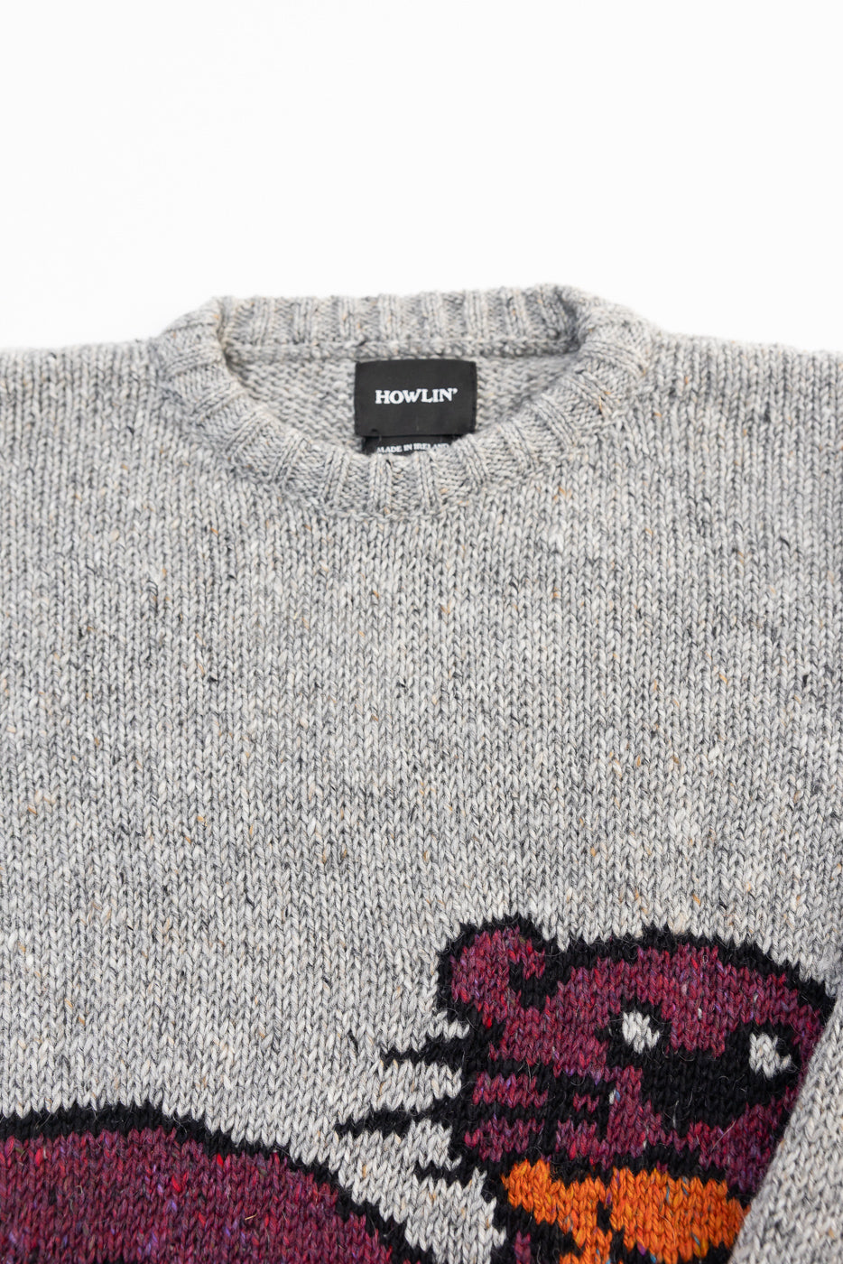 Close-up of Howlin' Stranger in Paradise Popover sweater, front chest and collar detail, grey knit with graphic, visible brand tag, at Dant contemporary casual apparel.