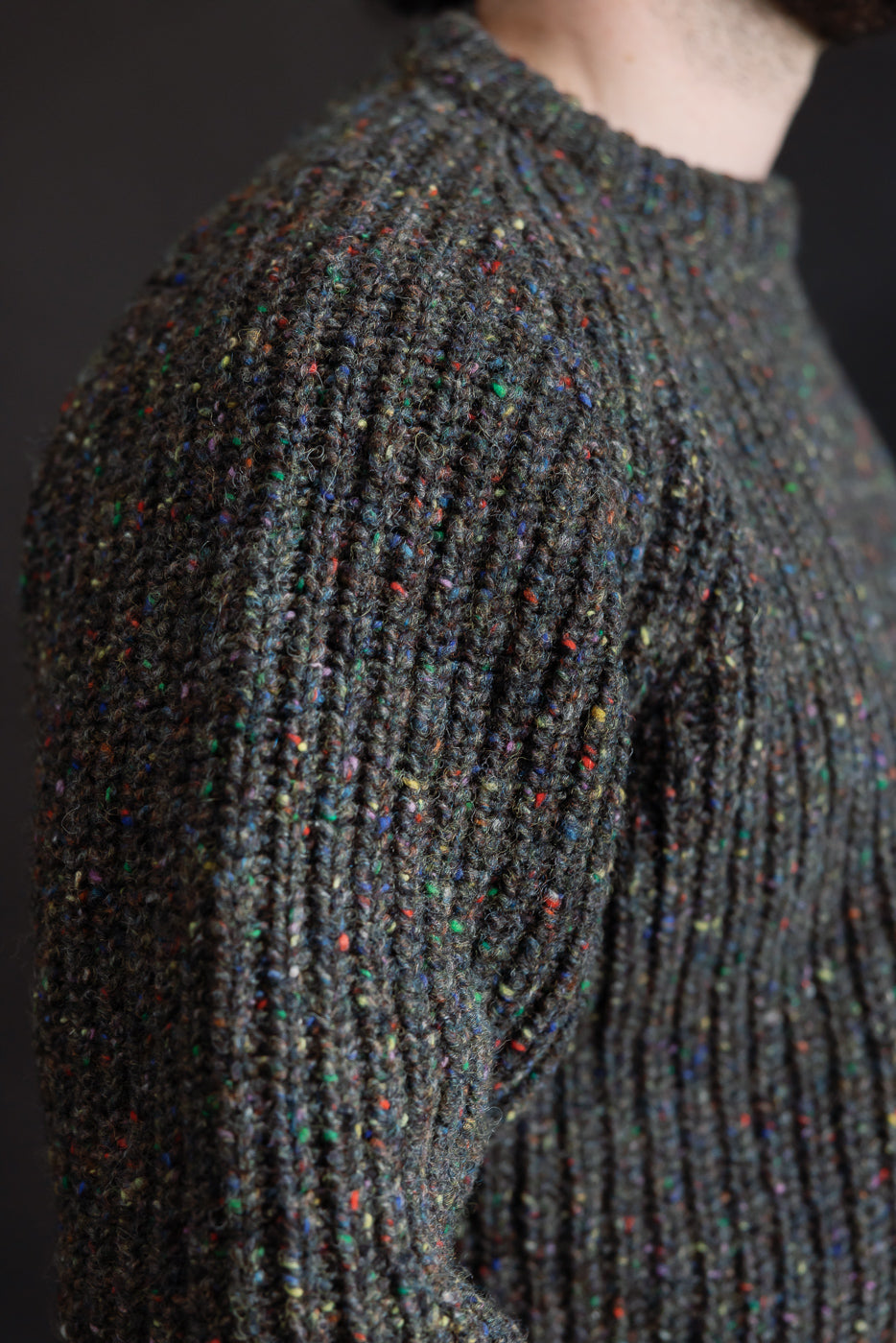 Close-up of men's speckled ribbed knit pullover shoulder and sleeve, athletic build, side view