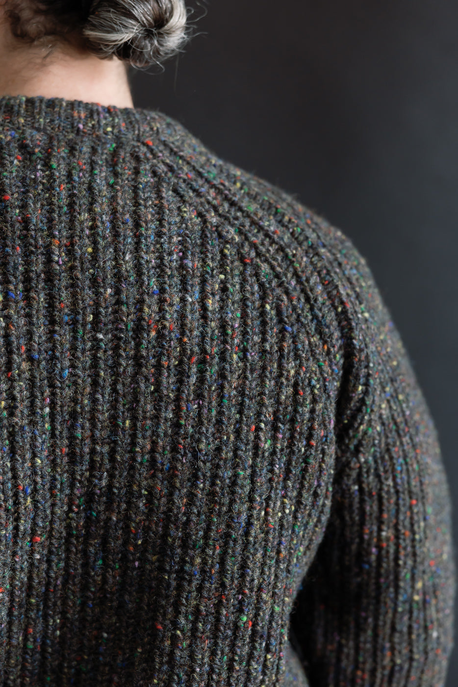 Close-up of male model's upper back in ribbed textured speckled knit pullover, back view