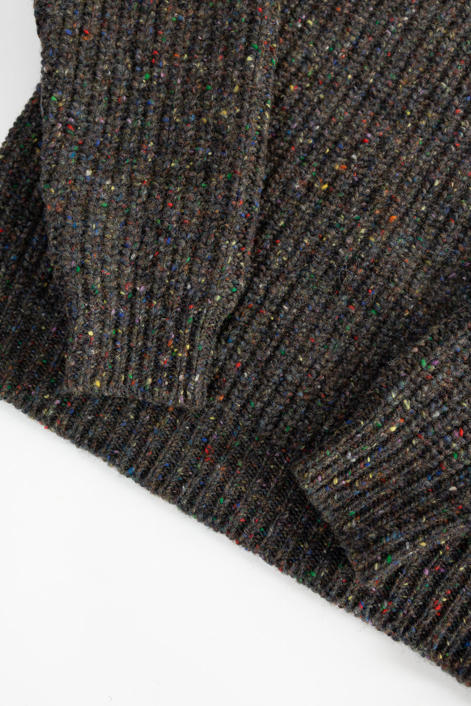 Close-up of ribbed multicolor speckled knit pullover sleeve and hem, front detail