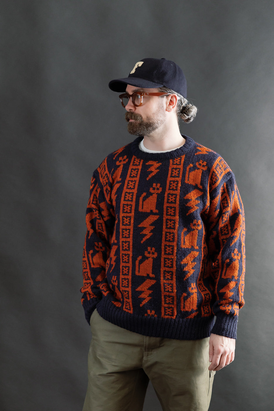 Male model 5'9, 165lbs, athletic build wearing Howlin' Thunder Cats Popover sweater, navy with orange cat and lightning knit, full front view, casual contemporary style for Dant store.