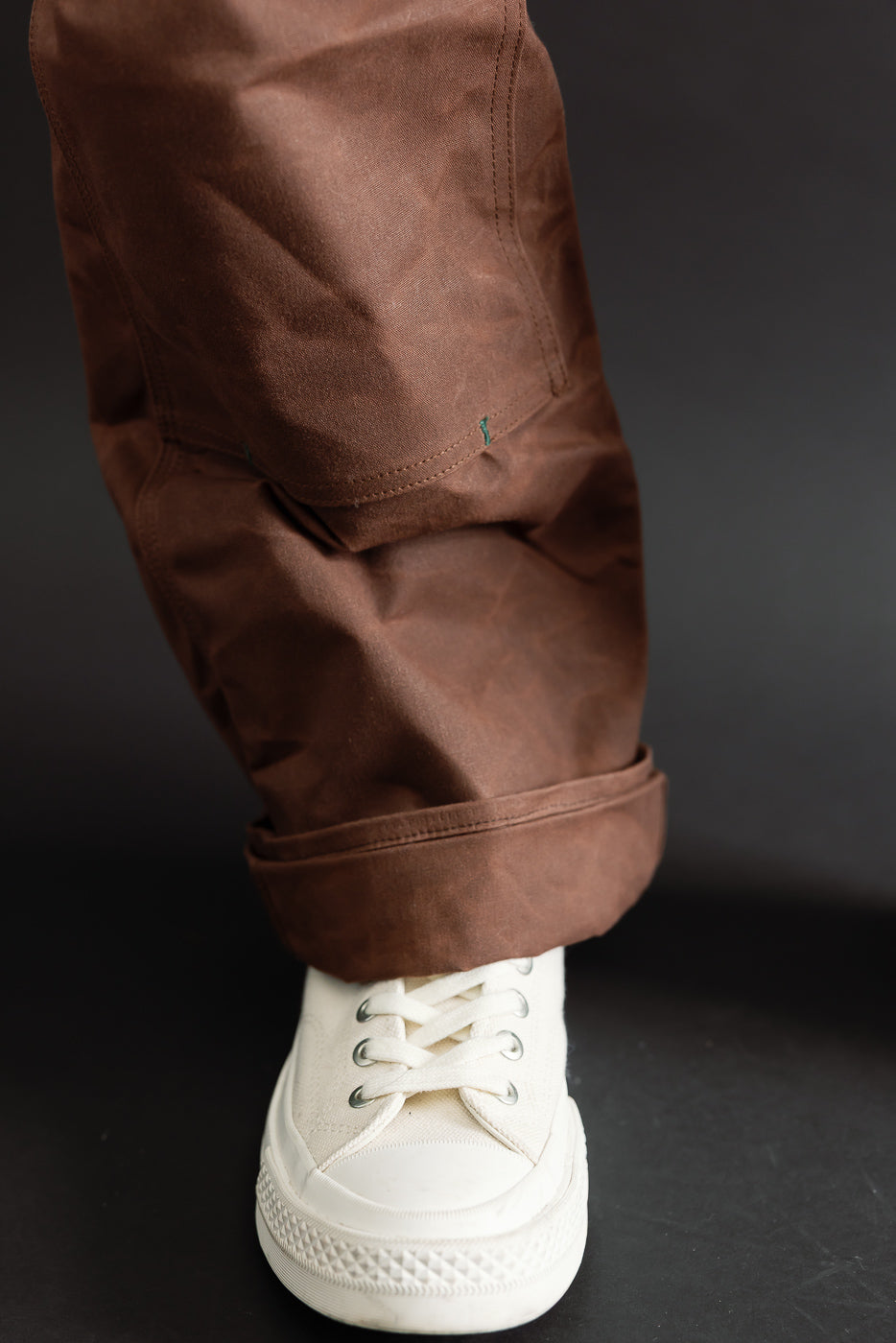 Close-up of the lower leg and cuff of brown canvas trousers worn by a male model, 5'9