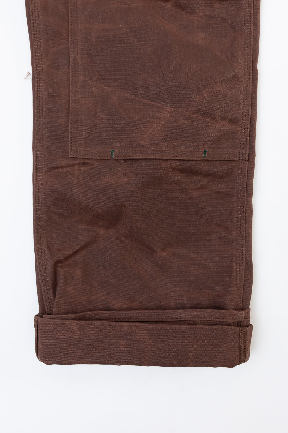 Flat lay, back view of brown canvas work pants showing large rear patch pocket and cuffed hem.