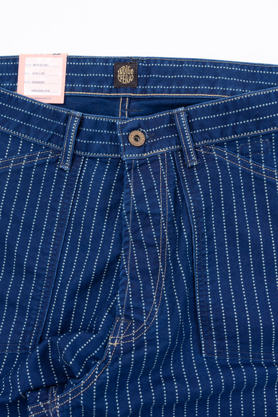 Close-up of the front waistband of blue pinstripe pants featuring a button and tag.