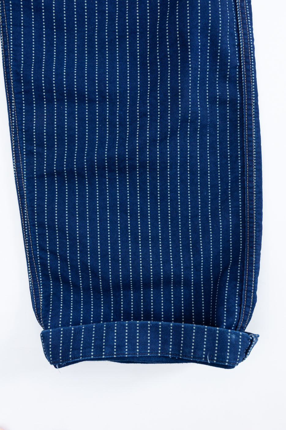 Close-up of the bottom hem of blue pinstripe trousers, front view.