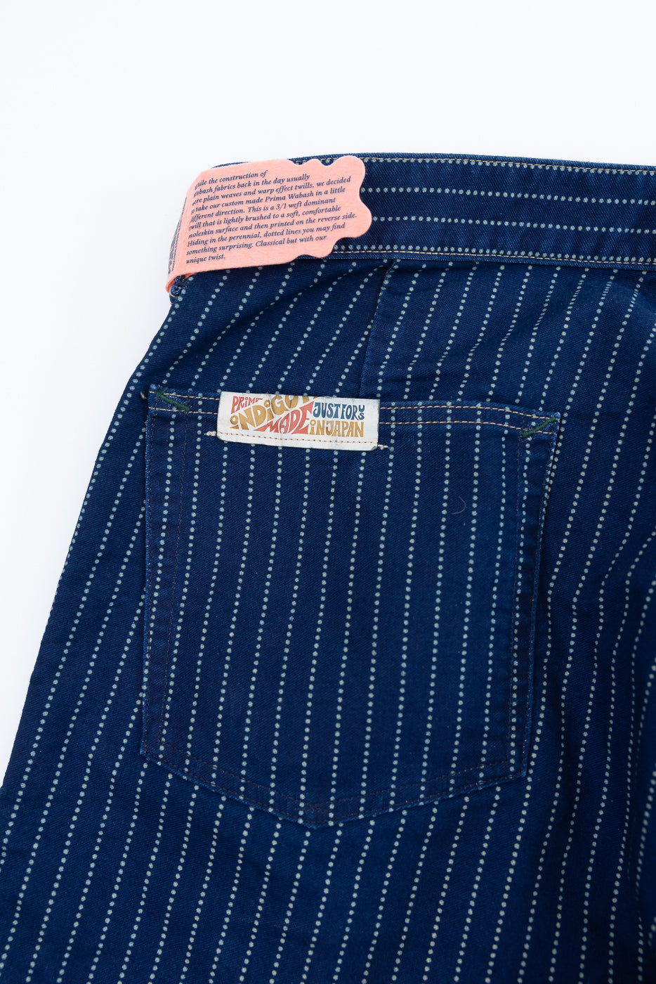 Close-up of back pocket on blue dotted pants featuring a brand tag and fabric label.
