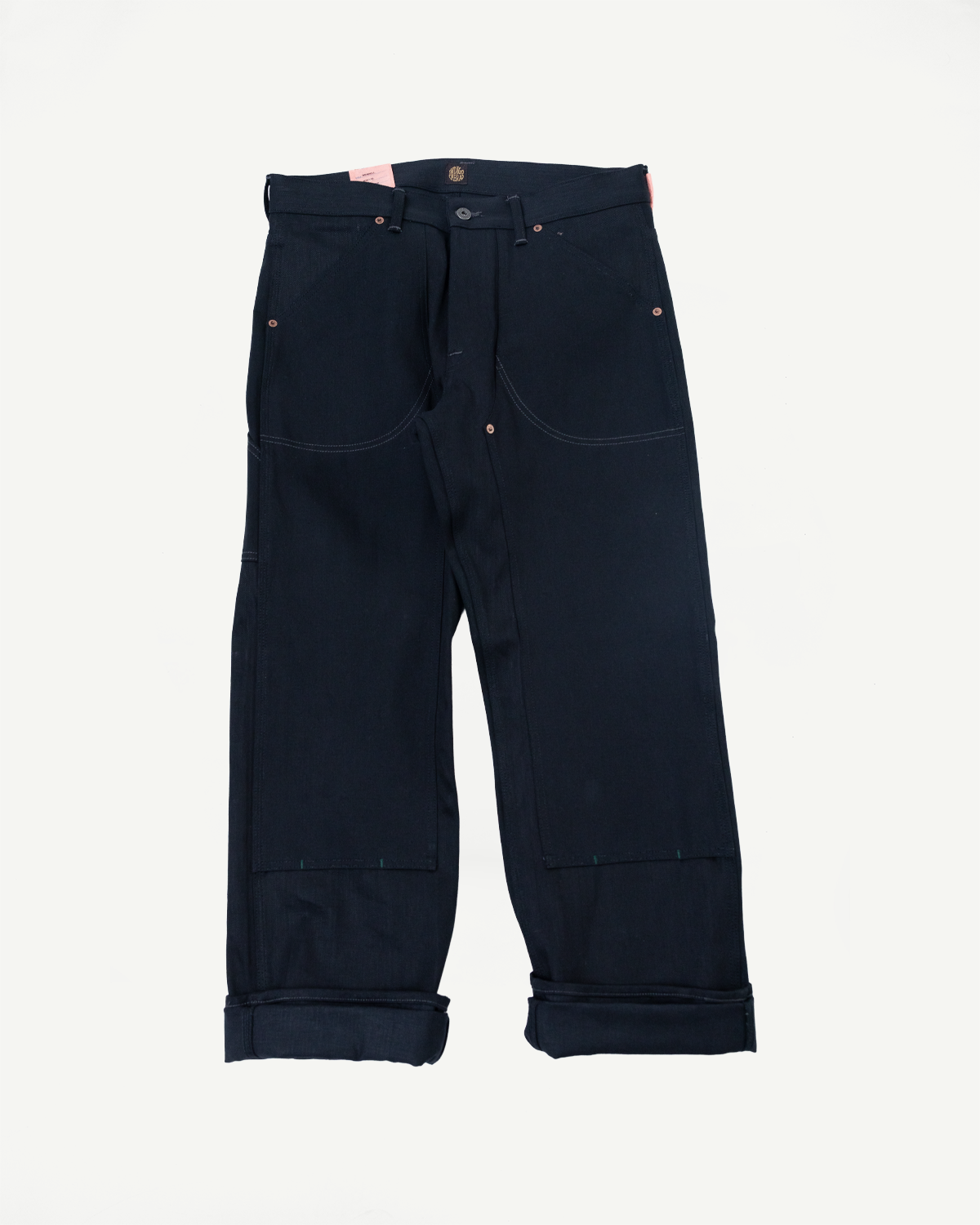Front view of dark selvedge denim pants with cuffed hems, copper rivets, and front pockets