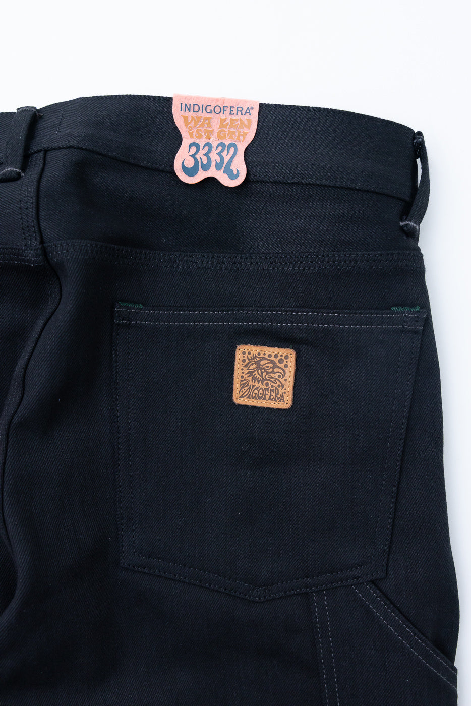 Close-up of dark selvedge jeans back, showing Indigofera tag and leather patch detail