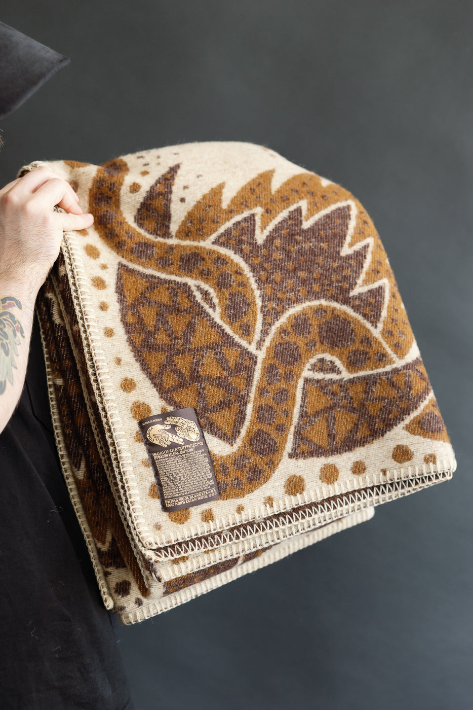 folded brown and beige blanket on a white background with custom artwork tag in lower left corner, close up