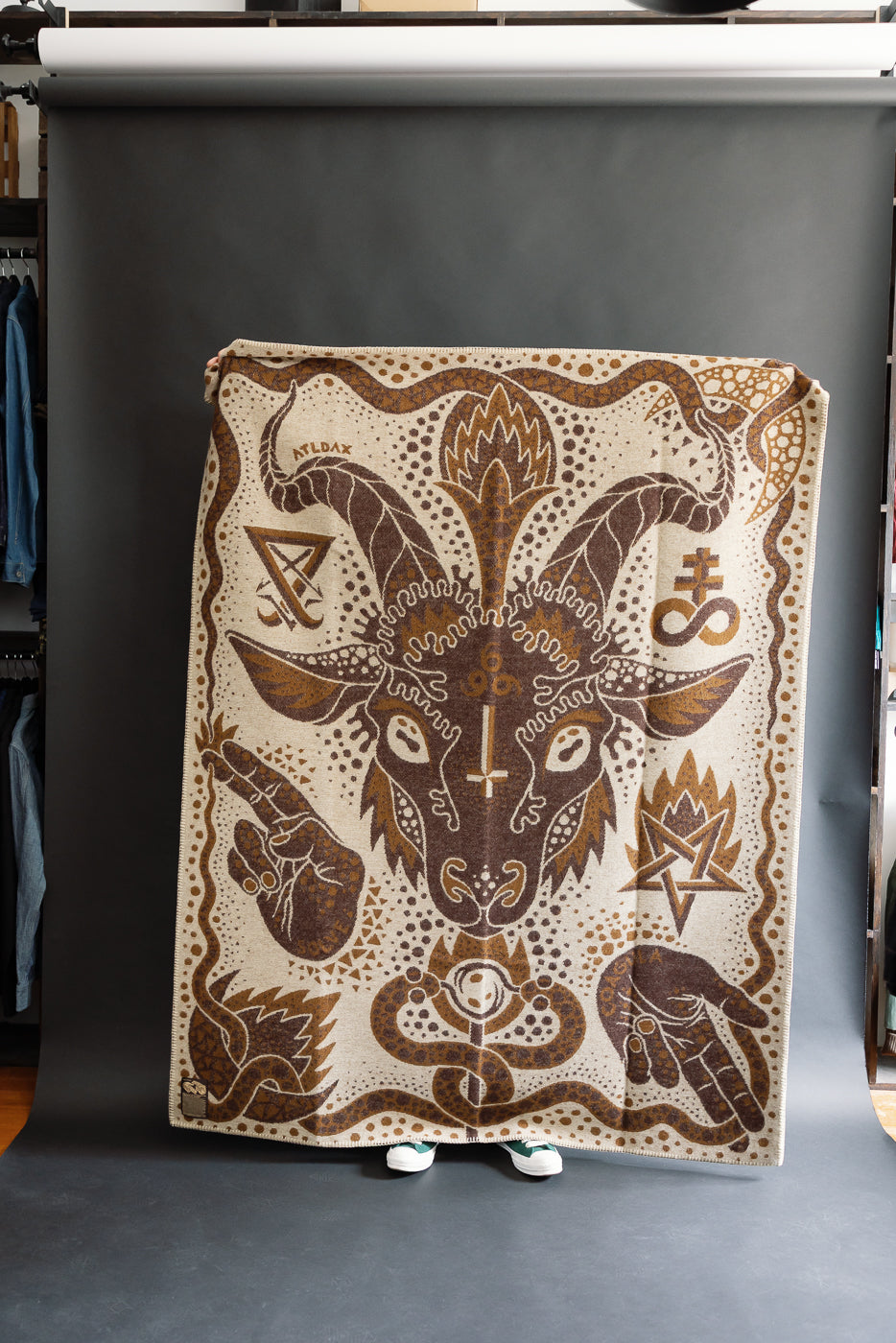fully open brown and beige blanket on a black background with custom artwork of baphomet, hands, serpent, and other sigils