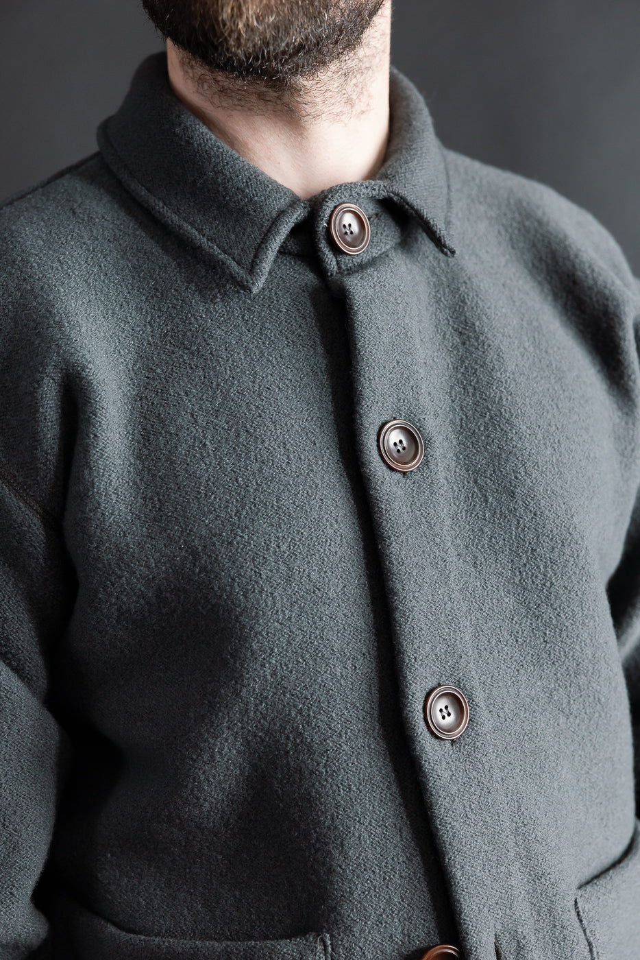 Close-up front view of Indigofera Brewster dark grey boiled wool shirt on male model, 5'9