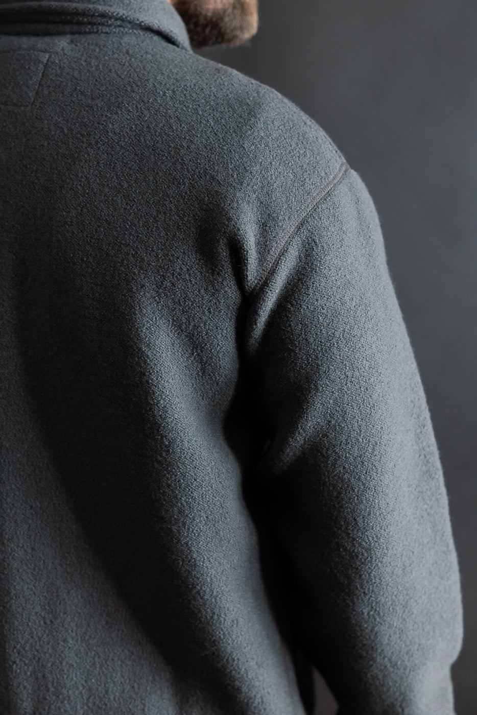 Close-up of men's Indigofera Brewster shirt, boiled wool, dark grey, back right shoulder view, model is male, 5'9