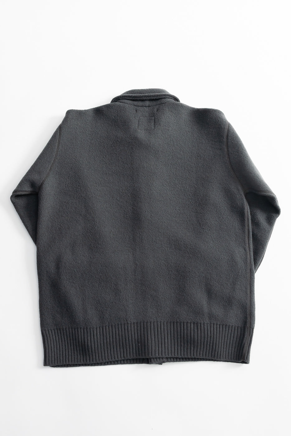 Back view of indigofera Brewster shirt in boiled wool dark grey, laid flat on white background