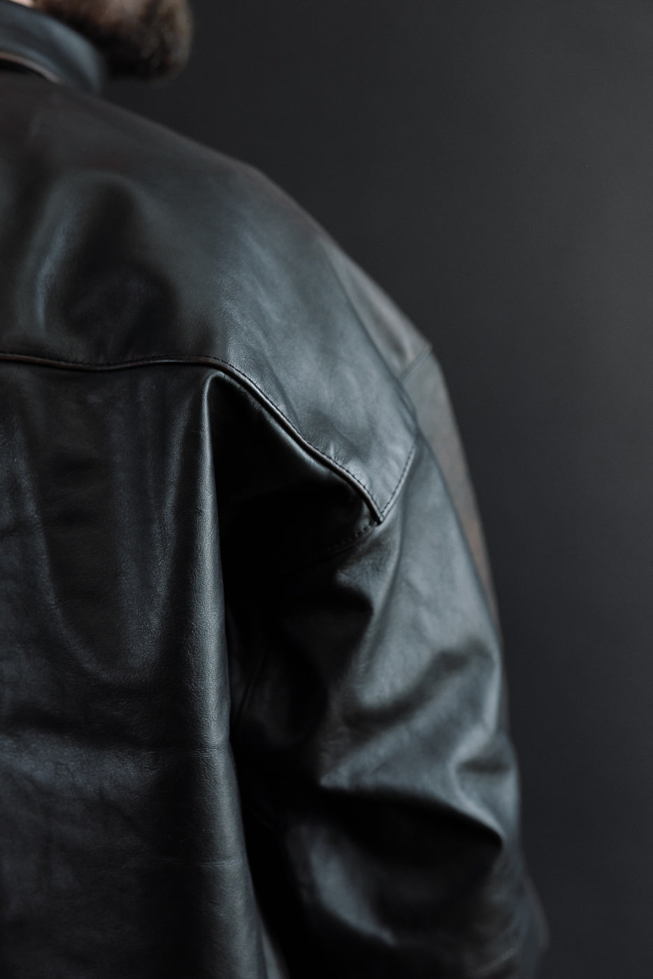 Close-up of the back and shoulder of a black leather jacket on a male model, 5'9