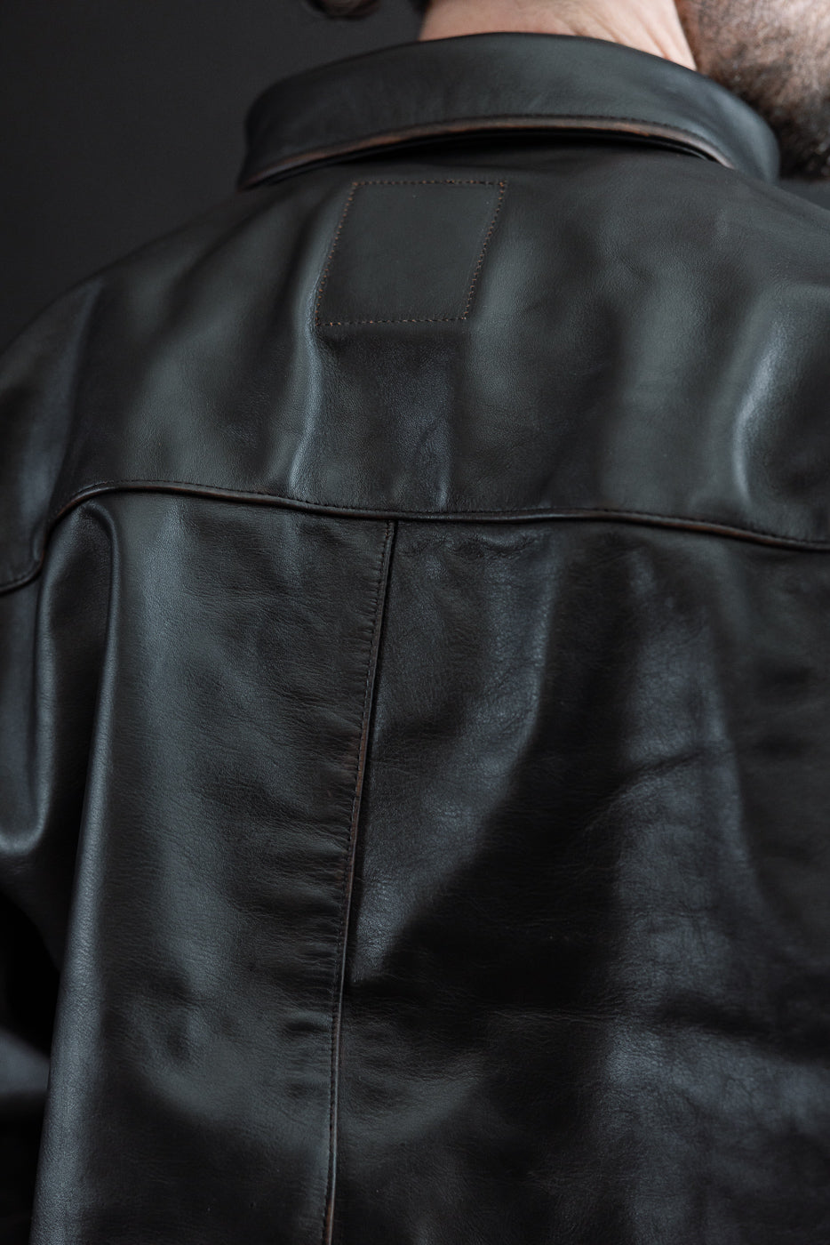Close-up back view of a black leather jacket on a male model, 5'9