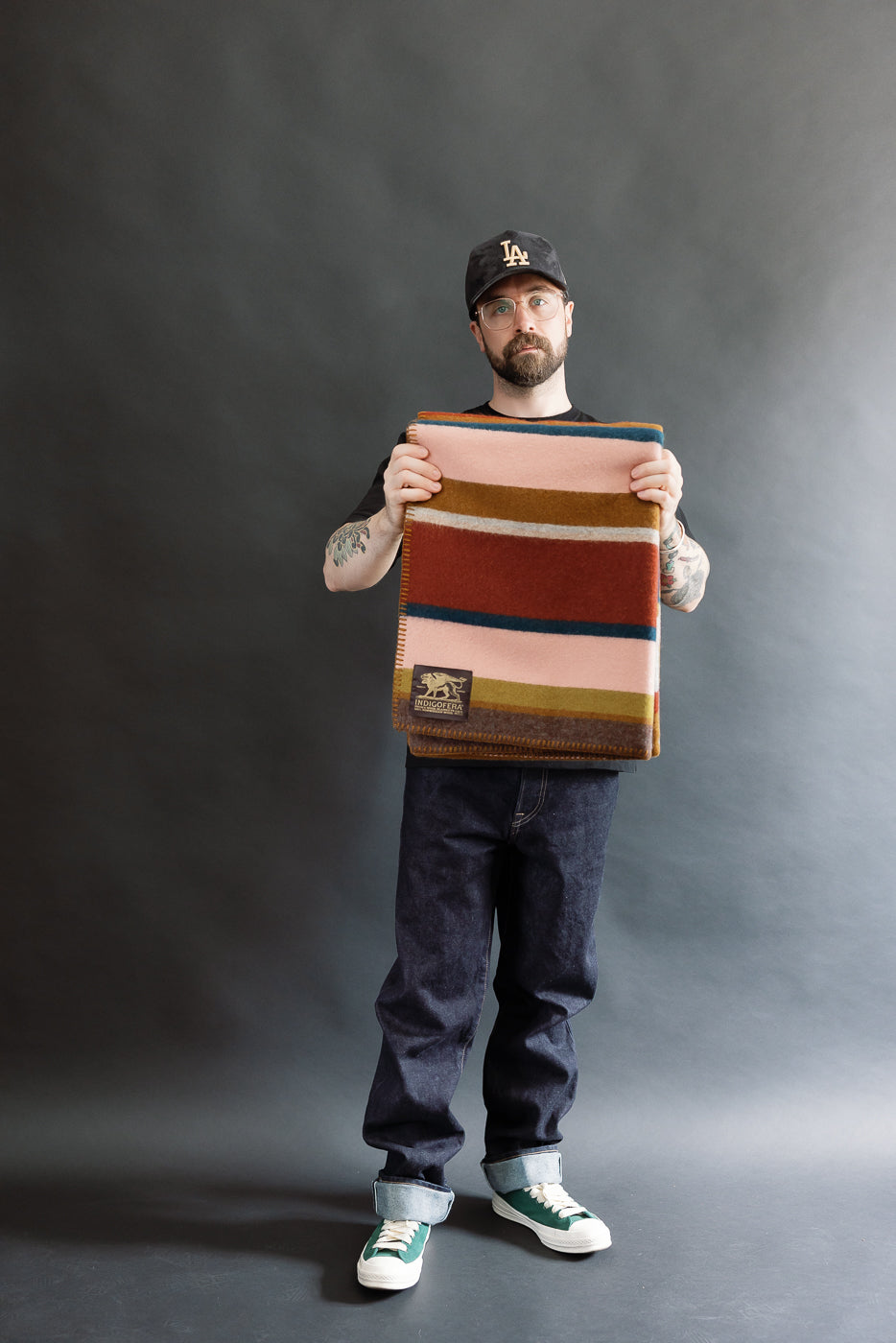 Man holding a striped blanket against a black background