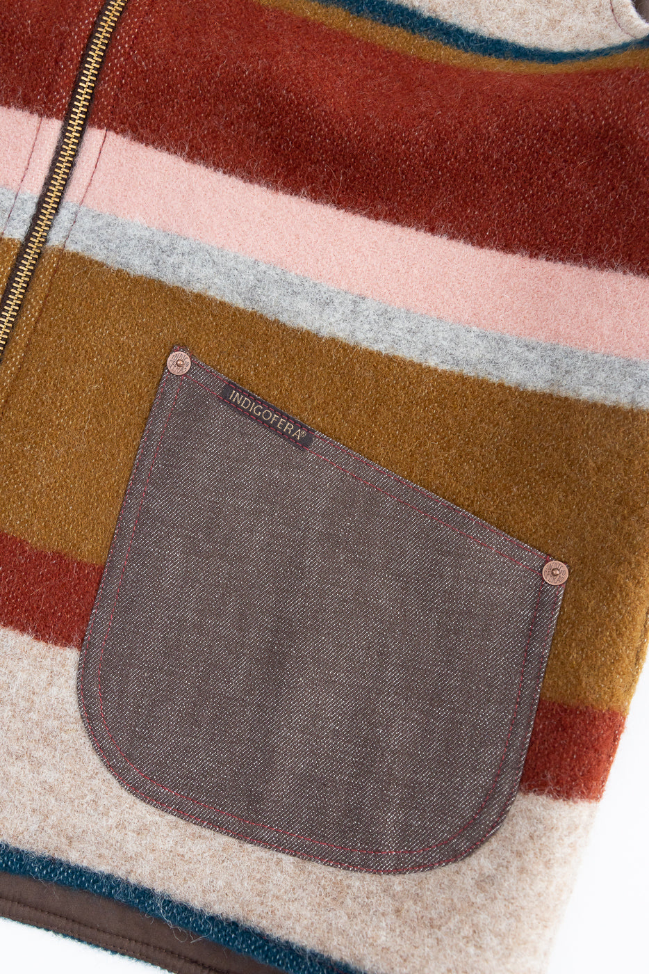 Close-up front view of striped wool jacket pocket with INDIGOFERA tag, copper rivets, red stitching, and zipper detail