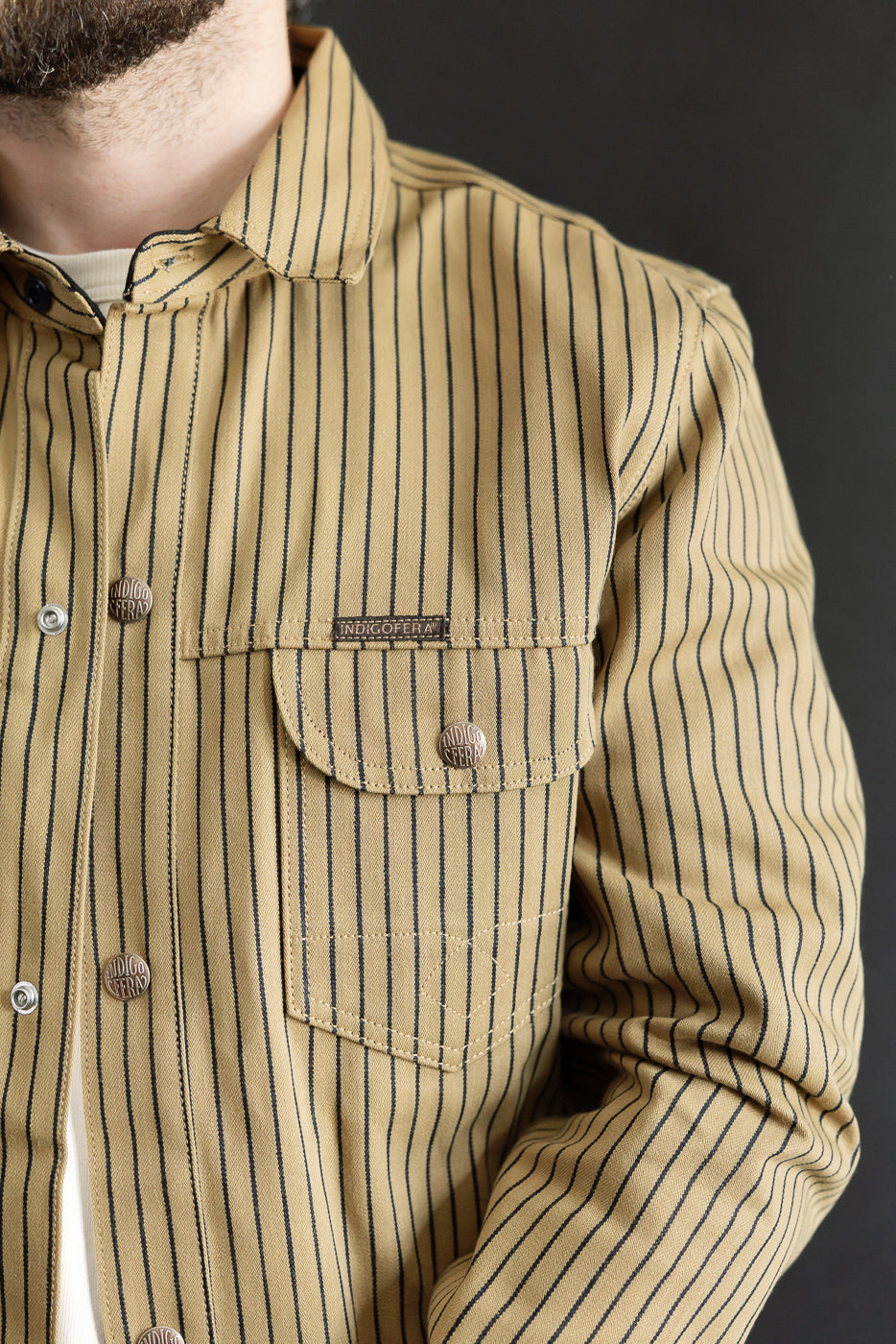 Close-up of front chest area of beige and indigo striped shirt jacket on male model, 5'9