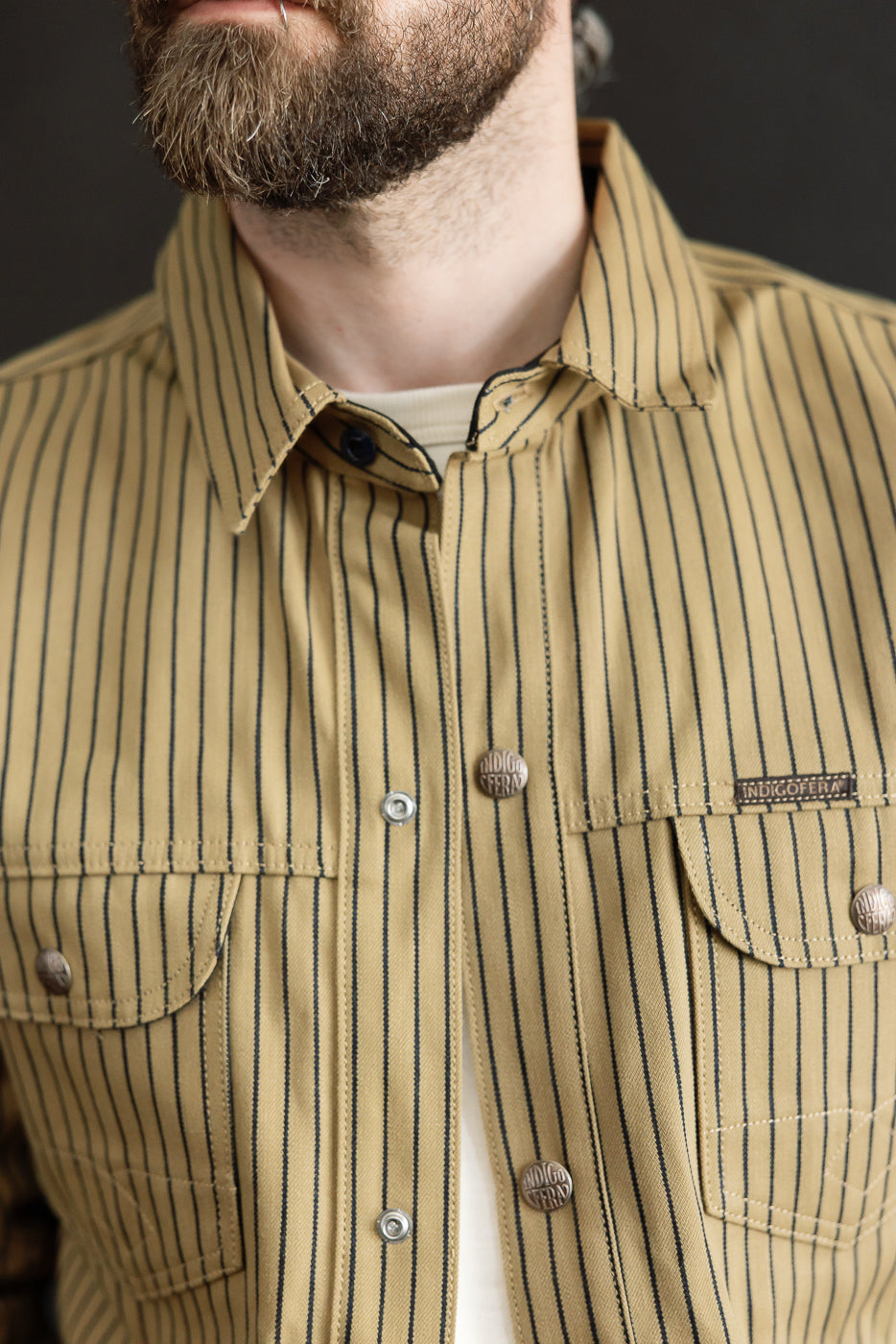 Close-up front view of beige and indigo striped shirt jacket on male model, 5'9
