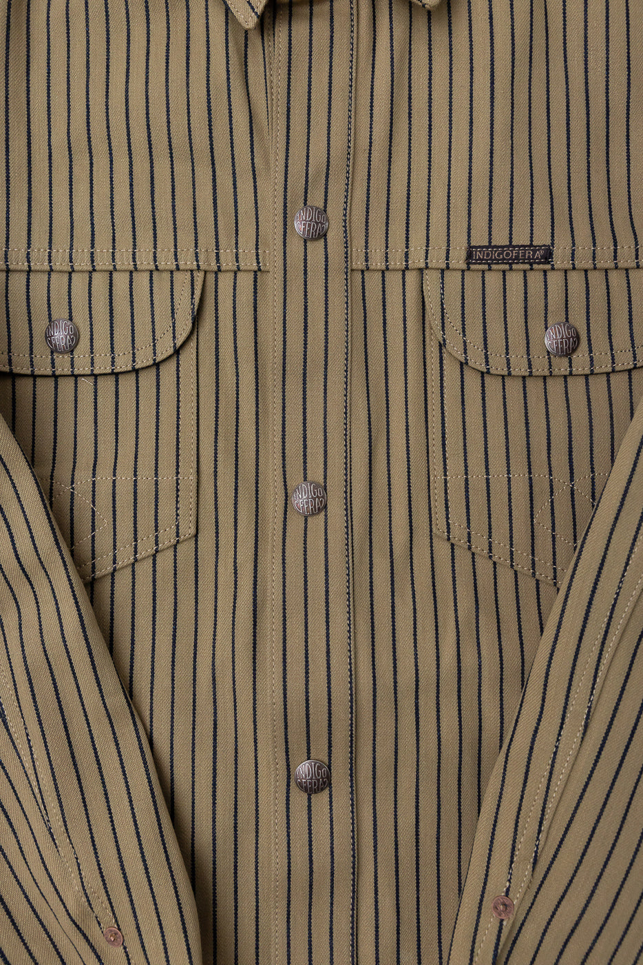 Close-up front view of striped beige and indigo shirt, snap buttons, chest pockets, fabric texture