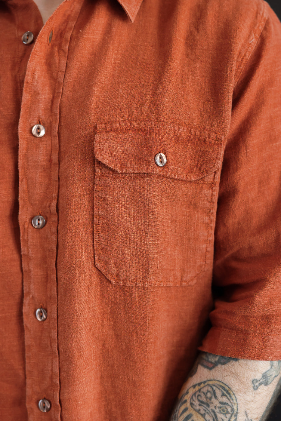 Close-up front view of rust linen shirt, male model, athletic build, showing chest pocket and buttons