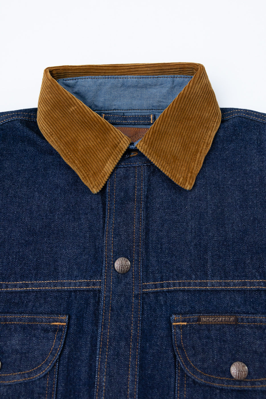 Close-up front view of indigo denim shirt with corduroy collar, button details, and chest pockets