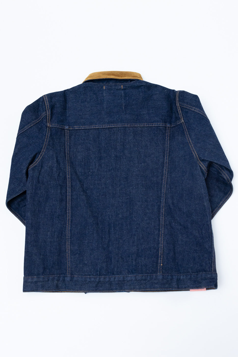 Back view of dark denim jacket with corduroy collar, flat lay, selvedge detail