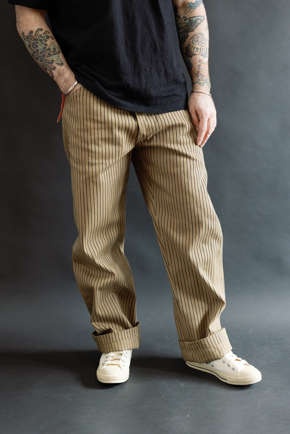 Front view close-up of beige indigo pinstripe pants on male model, 5'9