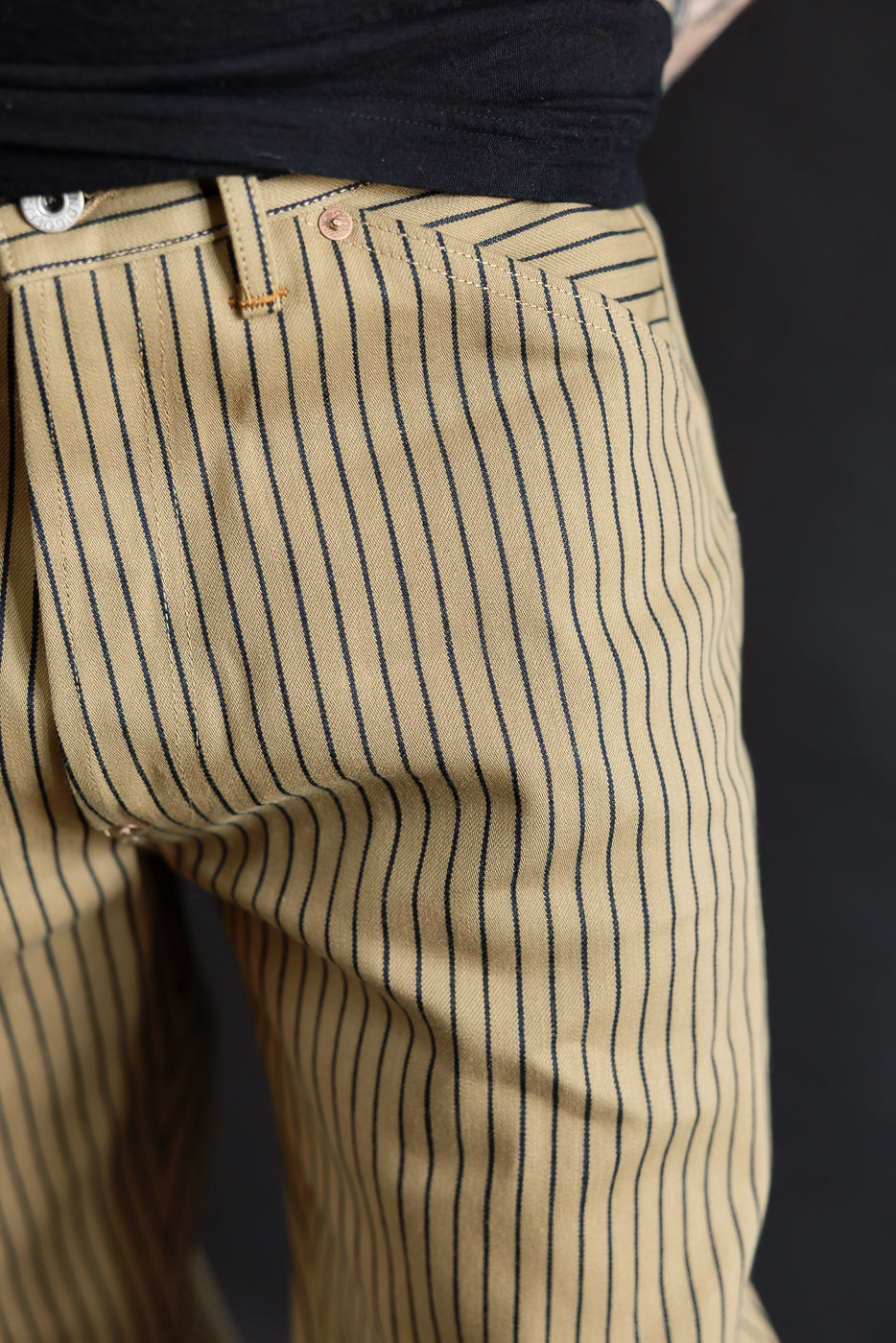 Close-up front view of beige indigo striped pants on male model, 5'9