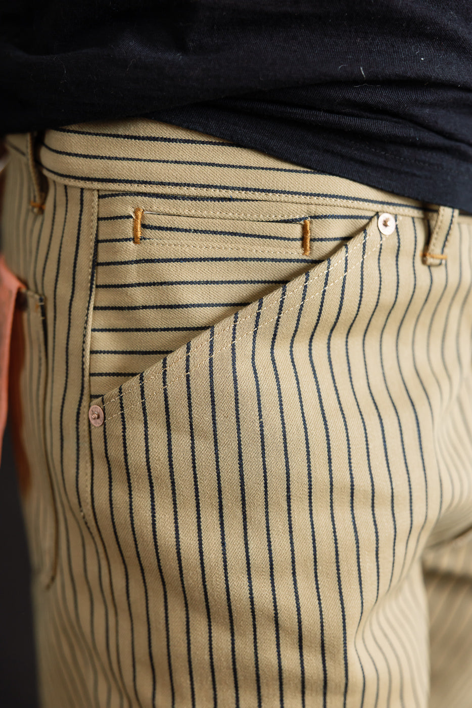 Close-up of front right hip and pocket on beige pants with indigo vertical stripes, male model, 5'9