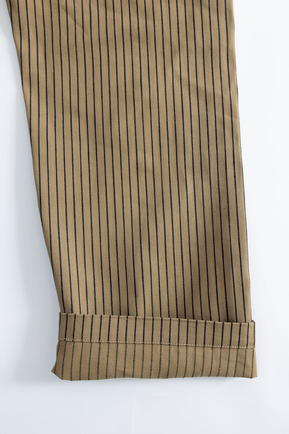 Close-up of beige and indigo striped pant leg, front view, showing fabric texture and cuff hem.