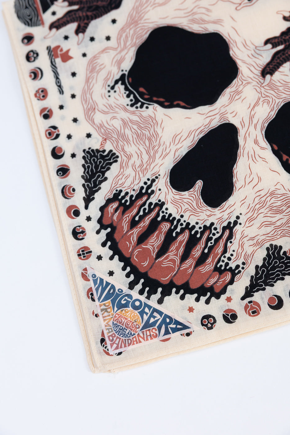 Close-up of the front of a bandana showing a skull graphic and a sewn-in brand tag.