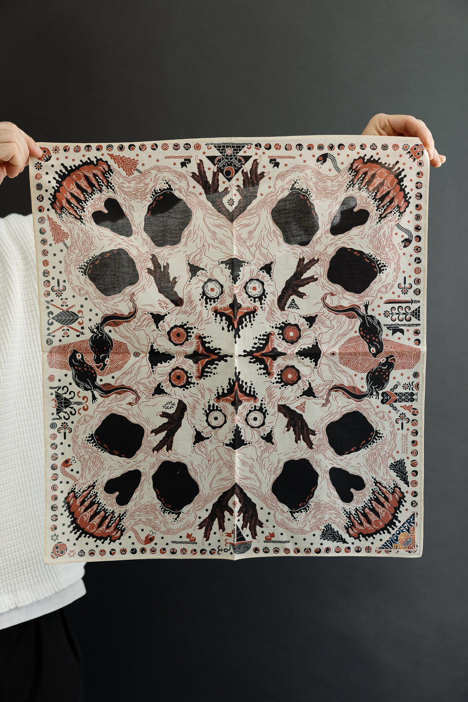 Close-up front view of a patterned bandana held by a male model, 5'9