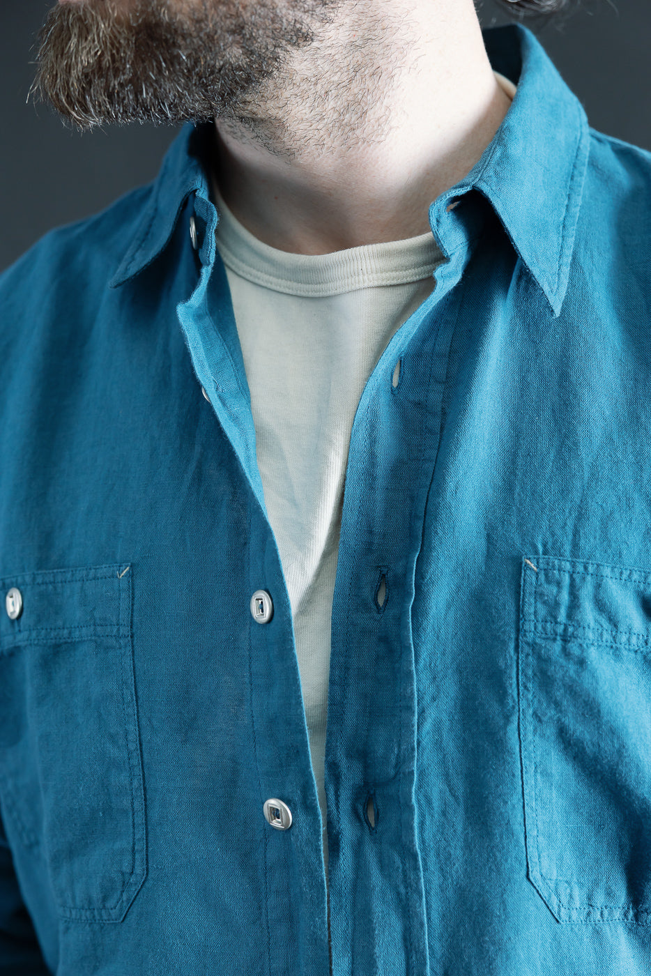 Close-up front chest view of Indigofera McAllen ocean blue canvas shirt on male model, 5'9