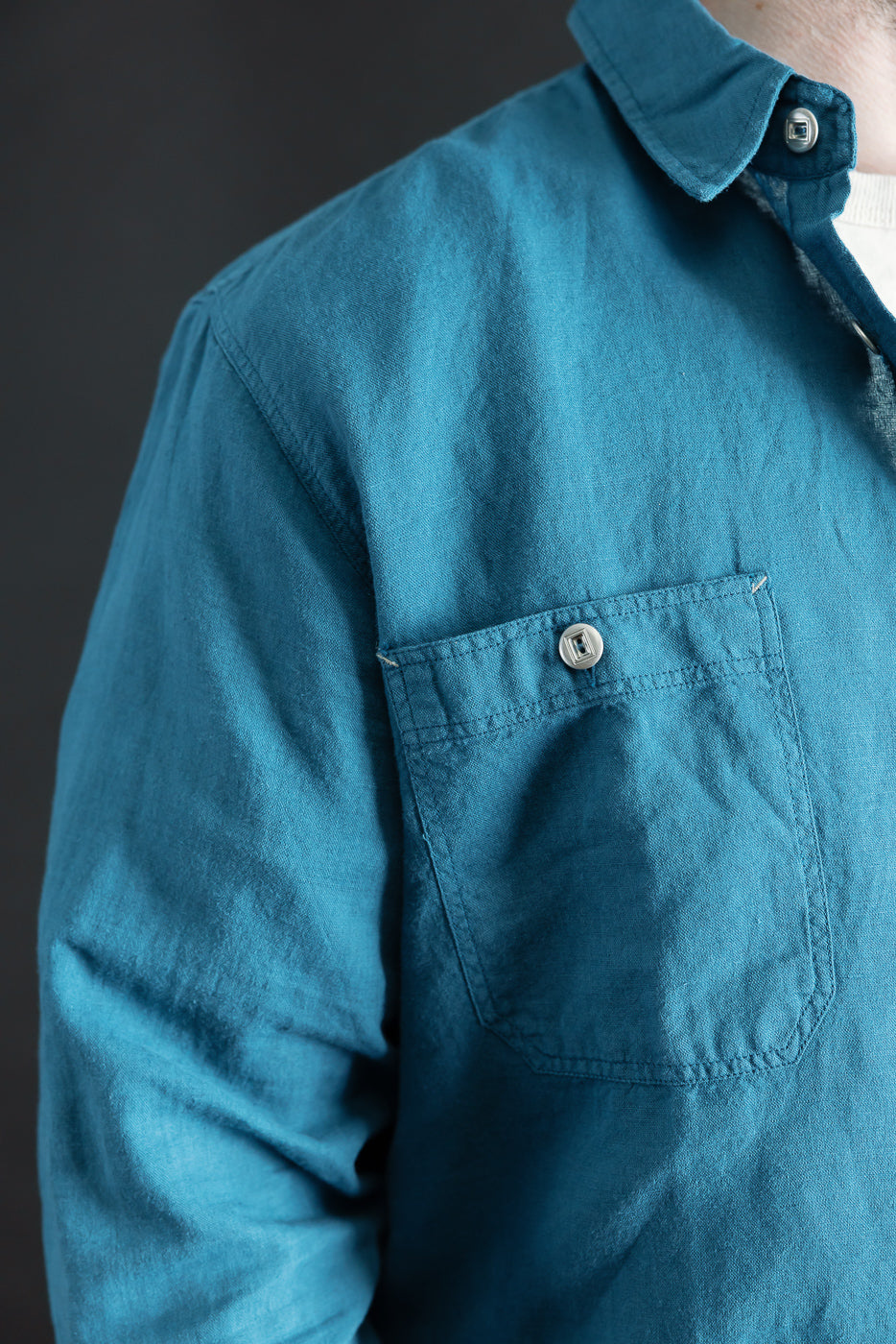 Close-up of men's indigo blue canvas shirt front chest pocket and button detail, male model 5'9